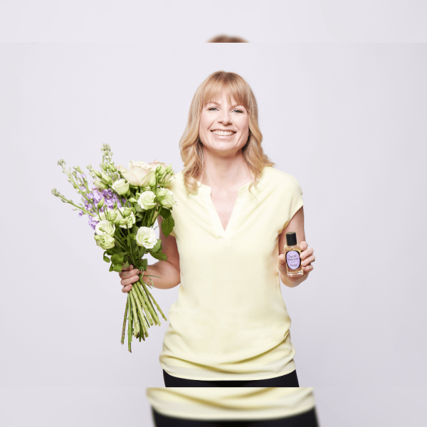 une femme qui tient un bouquet de fleurs et un parfum